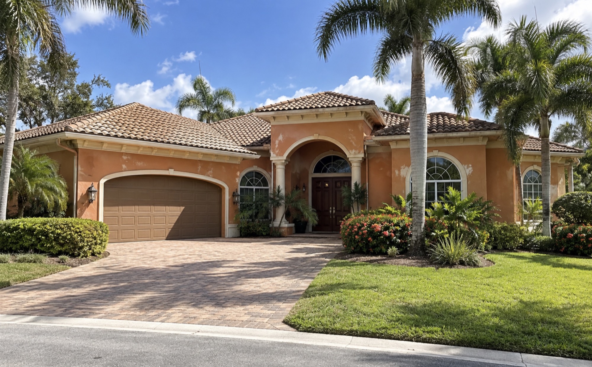 Mediterranean-style house in The Moorings, Naples, FL before exterior painting, with faded, stained orange stucco walls, a tile roof, and palm trees