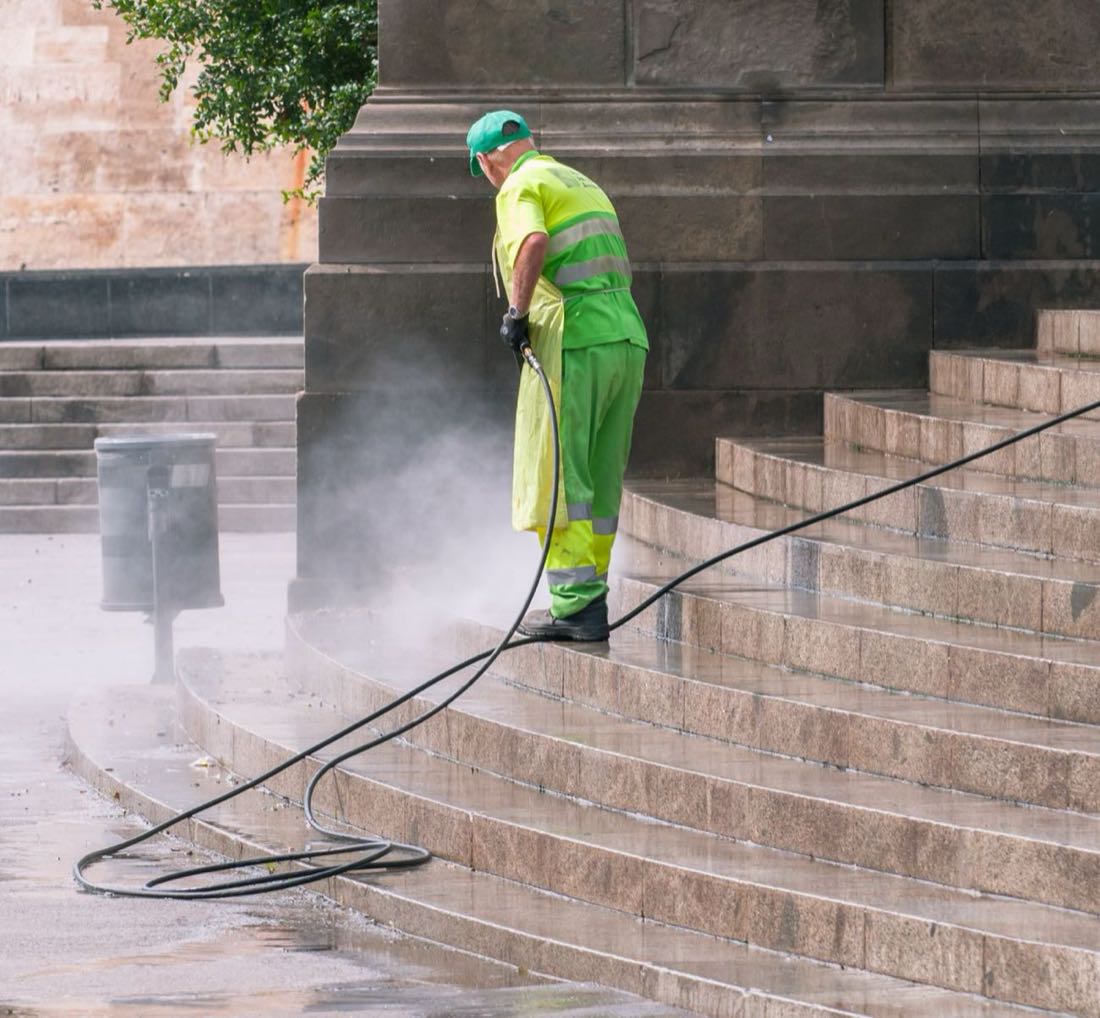 Worker pressure washing an outdoor surface before a paint job